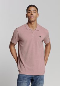 Polo shirt in lichtroze, korte mouwen, geknoopte kraag, zwart hexagonaal logo op de borst, gemaakt van een zachte katoenmix.