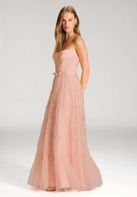 Satin pink gown ilman hihnoja kerroksittain tullea, jossa on tiukka yläosa ja solki vyötäröllä, ja joka sisältää lentävää, kerroksellista hameosaa.