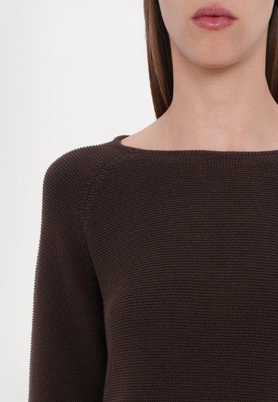 Pull en maille marron avec un large col et une texture côtelée, présentant des épaules légèrement tombantes visibles en gros plan.