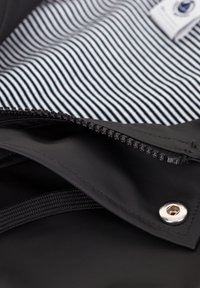 Zwarte zippered tas met een gestreepte binnenvoering, duurzaam materiaal en een zilveren hardware detail. De banden zijn geïntegreerd in het ontwerp.