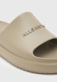 Sandală deschisă bej, din material texturat. Prezintă logo-ul embosat "ALLSAINTS" și o talpă zimțată pentru aderență.