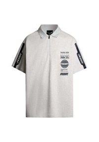 Siva polo majica z zadrgo pri ovratniku, ki ima črno blagovno znamko in grafike na prsih in rokavih. Mehka tkanina s sproščenim krojem.