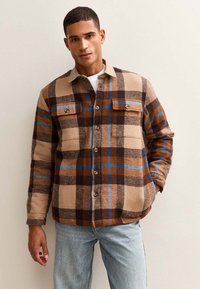 Brown and beige plaid shirt jacket with blue accents, featuring a buttoned front, two chest pockets, and a soft texture.