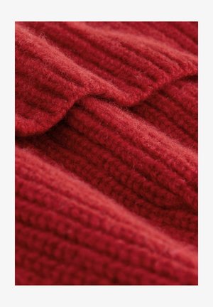 Roter Strickstoff mit strukturiertem Rippenmuster. Weiche, flauschige Oberfläche mit überlappenden Falten, die Tiefe und Wärme zeigen.