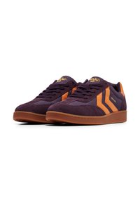 Lila Sneakers aus Wildleder und Mesh, mit orangen Streifen und Schnürsenkeln, einer braunen Gummisohle und strukturierten Details.