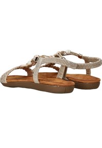 Sandales tressées beiges avec des brides texturées, ornées de perles blanches, et une semelle intérieure rembourrée marron ainsi qu'une semelle en caoutchouc flexible.