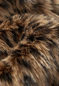 Faux fur stof i brune og sorte nuancer, med en blød tekstur, der har varierende længder og naturligt udseende striber, hvilket skaber dybde og blødhed.
