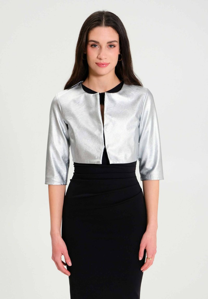 Zilverkleurige metallic cropped jas met driekwartmouwen, ronde halslijn en zwarte accenten, gecombineerd met een aansluitende zwarte jurk.