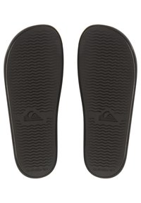 Sorte flip-flop såler laget av gummi, med et strukturert bølgete mønster for grep og en logodetalj nær hælen.