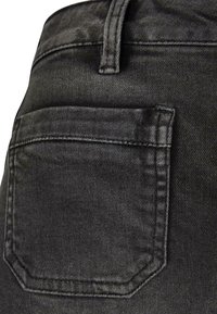 Melnas denima audums ar aizmugurējo kabatu, kurai ir izšūta kontūra. Auduma faktūra izskatās gluda ar nedaudzām krāsas variācijām.