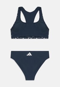 Mørkeblå to-delt bikini sæt, der har en sports-bh med racerback-design og en bunden med hvidt logo. Glat, strækbart stof med prikker.