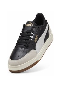 Black and white sneaker featuring leather and suede materials, round toe design, perforated detail on the black upper, and a beige rubber sole.