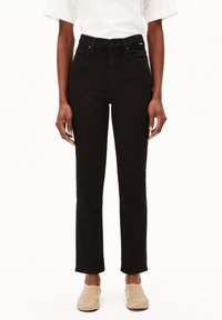 Jean noir taille haute, coupe slim, avec cinq poches et des coutures discrètes. Le matériau est en denim, présentant un design classique à jambes droites.