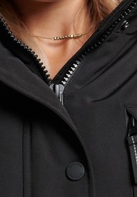 Černá bunda na zip po celé délce s vysokým límcem, vyrobená z texturované tkaniny, s plastovými knoflíky a předním kapsou na zip se proužkovaným tahem zipu.