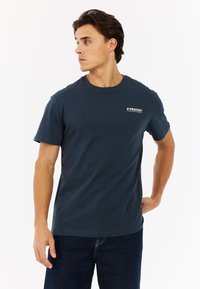 Marineblauwe katoenen T-shirt met ronde hals, korte mouwen en een klein wit logo op de borst. Soepele textuur, klassieke pasvorm, casual stijl.