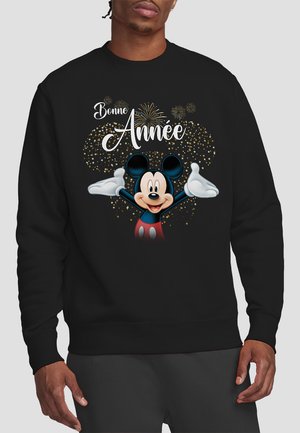 Schwarzer Sweatshirt mit einer bunten Grafik eines Cartoon-Charakters mit erhobenen Armen, umgeben von goldenen Funkeln und dem Text "Bonne Année."