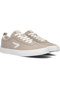 Beige suede sneakers met witte veters en een rubberen zool. Voorzien van een logo en een opvallende witte accent aan de zijkant. Lage ontwerp.