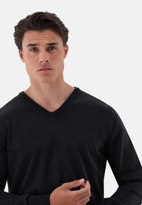 Dunkelgrauer V-Ausschnitt-Pullover aus weichem Material; lange Ärmel;figurbetontes Design mit minimaler Textur und ohne sichtbare Muster oder Akzente.