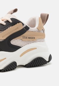Sneaker chunky caratterizzato da faux leather nero, rete beige e suola in gomma bianca. Include il marchio "Steve Madden" sul lato. Suola testurizzata.