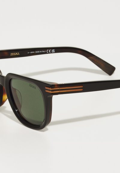 Tortoiseshell sunglasses with green lenses, rectangular shape, glossy finish, gold accents on temples, engraved logo on frame and arms.
