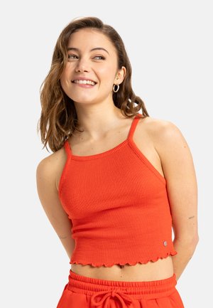 Red ribbed crop top with thin straps and a scalloped hem. Features a small logo accent on the side. Smooth, stretchy fabric.