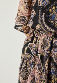 Zwarte jurk met paisley-patronen in roze, blauw en geel. Zachte, gestructureerde stof met een getailleerde taille en losse mouwen.