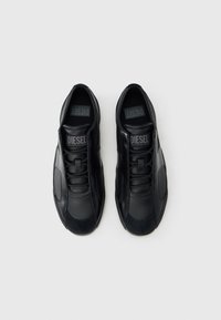 Črne superge z gladkim usnjenim zgornjim delom in tkaninskimi poudarki. Zapenjanje z vezalkami, oblazinjen jezik in vidno logotip na vložku.