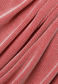 Rot-weißer gestreifter Stoff mit einer weichen Textur, der schmale vertikale Linien aufweist, die ein Muster aus abwechselnden Farben und Wellen erzeugen.