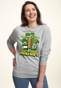 Felpa grigia con una grafica colorata di Minecraft. Il testo dice "MINA, NAP, RIPETI." Maniche e orlo a coste. Tessuto morbido.