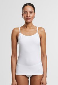 White tank top with thin straps, made of soft cotton material. Fitted design, smooth texture, and a classic scoop neckline.