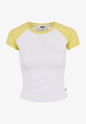 Fehér pamut póló sárga raglán ujjakkal. Környakú és fitted kialakítású. Címke látható a bal alsó sarokban.