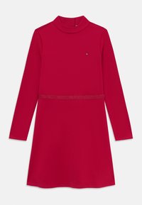 Robe longue rouge à manches longues avec un col montant, présentant une taille étroite et un petit logo. Fabriquée en tissu lisse et extensible.