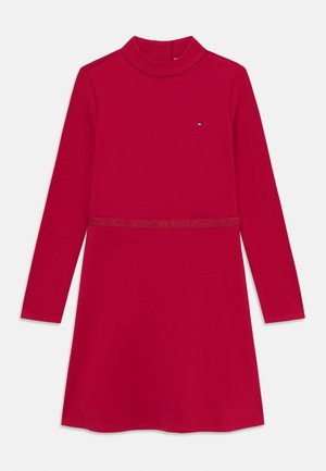 Robe longue rouge à manches longues avec un col montant, présentant une taille étroite et un petit logo. Fabriquée en tissu lisse et extensible.