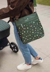 Tmavě zelená taška přes rameno s květinovým vzorem, kapsou na zip a nastavitelným popruhem. Materiál vypadá nepromokavě a má hladkou strukturu.