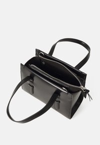 Sac à main en cuir noir, de forme rectangulaire avec une texture lisse, deux poignées, un compartiment zippé et des accents en métal argenté.