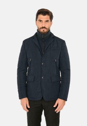 Giubbotto puffer navy con texture trapuntata, due tasche frontali con zip, chiusura con un singolo bottone e colletto alto. Materiale in poliestere liscio.