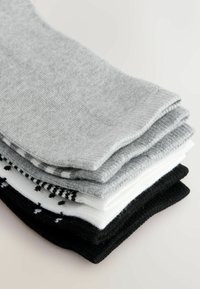 Neli paari sokke hallides, valgetes ja mustades toonides. Pehme kudumismaterjal, mõnel paaril erinevad mustrid, sealhulgas triibud ja täpid.