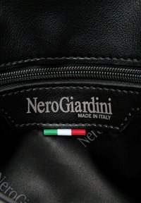 Sort læderinteriør med "NeroGiardini MADE IN ITALY" præget. Har et italiensk flagfarvet mærke, der fremhæver kvalitetsmaterialer og design.