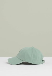Light green cotton baseball cap with a curved brim, adjustable strap, and a subtle logo embroidered on the front.