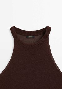 Haut marron sans manches avec un col montant arrondi et une texture côtelée. Comprend une étiquette à l'intérieur de l'encolure, affichant un design simple et minimaliste.