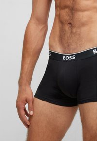 Boxeri negri pentru bărbați cu talie elastică, prezentând branding alb 'BOSS'. Materialul pare neted și ajustat, cu cusături minime.