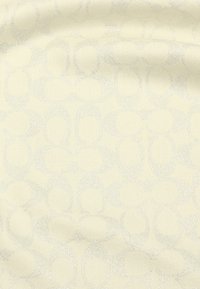 Cremefarbener Stoff mit einem subtilen, sich wiederholenden Muster aus miteinander verbundenen ovalen Formen in einem sanften, schimmernden Finish. Glatte Textur.