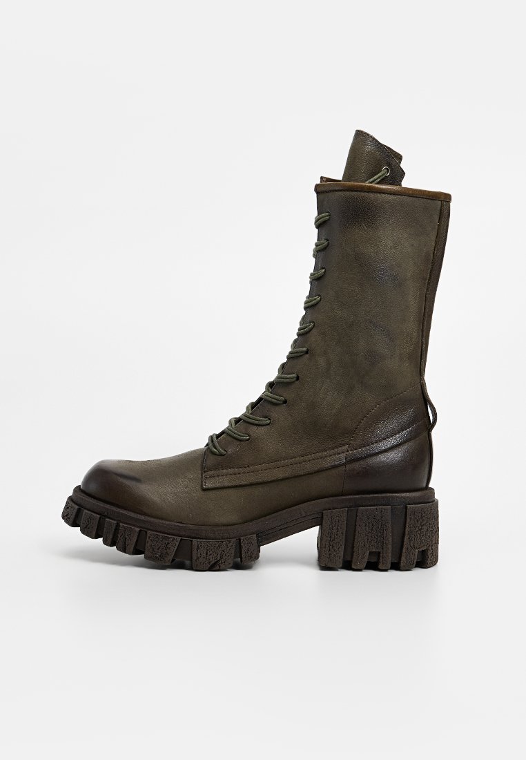Botte en cuir vert à lacets avec tige haute, semelle en caoutchouc épaisse et accents texturés. Dispose d'une boucle à l'arrière pour un enfilage plus facile.