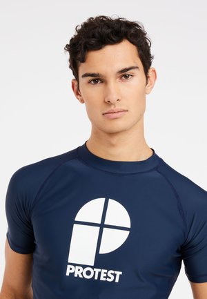 Mørkeblå rash guard fremstillet af strækbart materiale, med et fremtrædende hvidt logo i midten. Korte ærmer og rund halsudskæring.