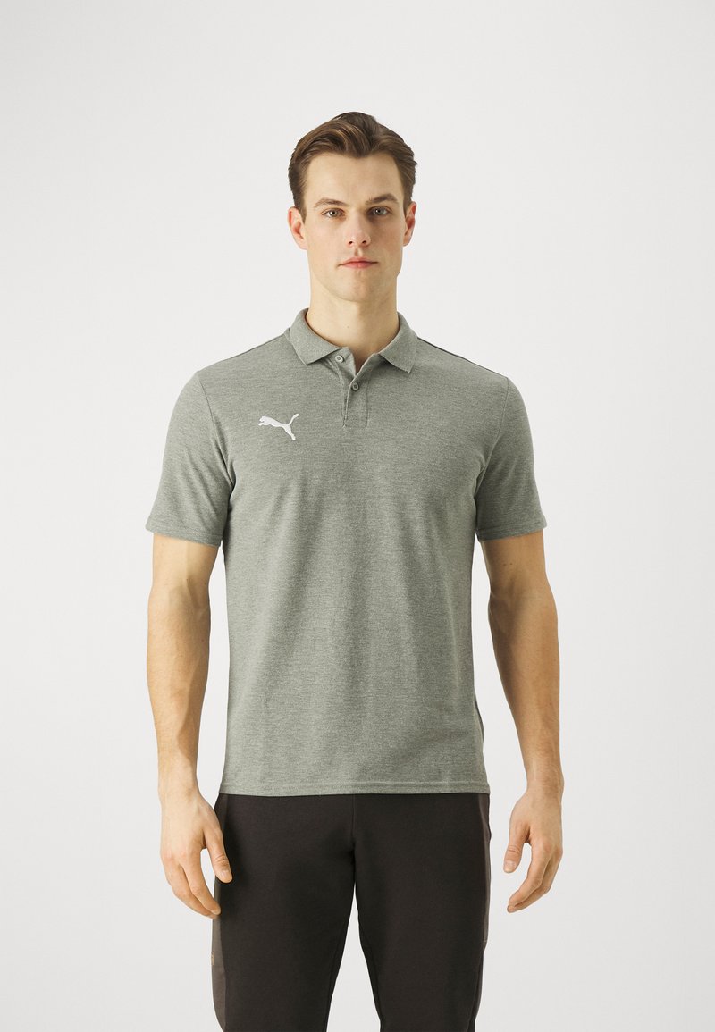 Šedé polo tričko s krátkými rukávy, vyrobené z texturované tkaniny. Na levé straně hrudi se nachází bílé logo a má klasický design límce.