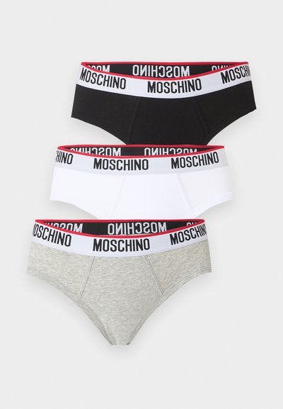 Τρία ανδρικά εσώρουχα σε μαύρο, λευκό και γκρι με λευκή ελαστική μέση που αναγράφει "MOSCHINO" με μαύρα γράμματα και κόκκινο περίγραμμα στην κορυφή.