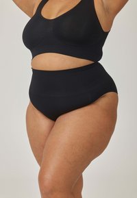 Czarny zestaw odzieży sportowej z bezszwowym biustonoszem z wycięciami i szortami z wysokim stanem. Gładka tekstura i dopasowany krój.