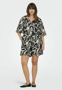 Ensemble abstrait noir et crème avec un haut à manches courtes ample et un short assorti, fabriqué à partir d'un tissu léger.