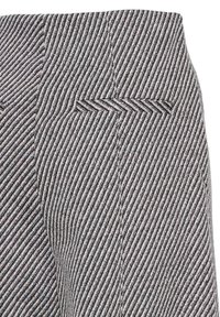 Sort og hvid stribet stof med fiskebenmønster. Nærbillede af en linning med subtile syninger og en baglomme.