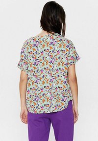 Blusa a maniche corte in tessuto verde menta con un motivo floreale che presenta fiori viola, arancioni e rosa; vestibilità comoda e orlo curvo.